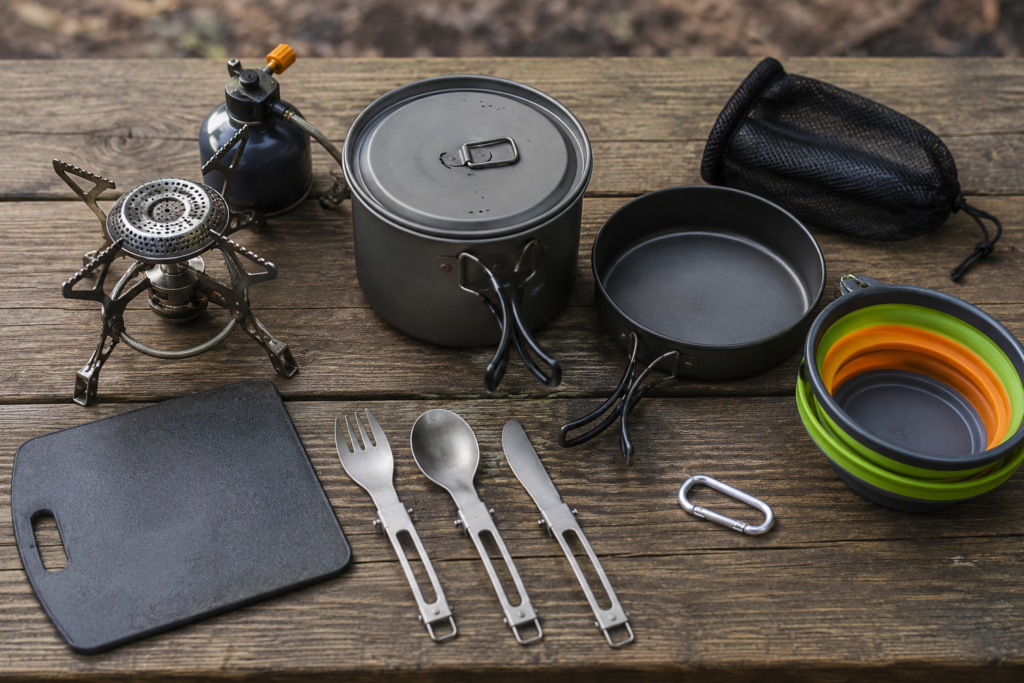 easy camp cooking beginners essential gear compact camp stove pot pan utensils and cutting board laid out camp table