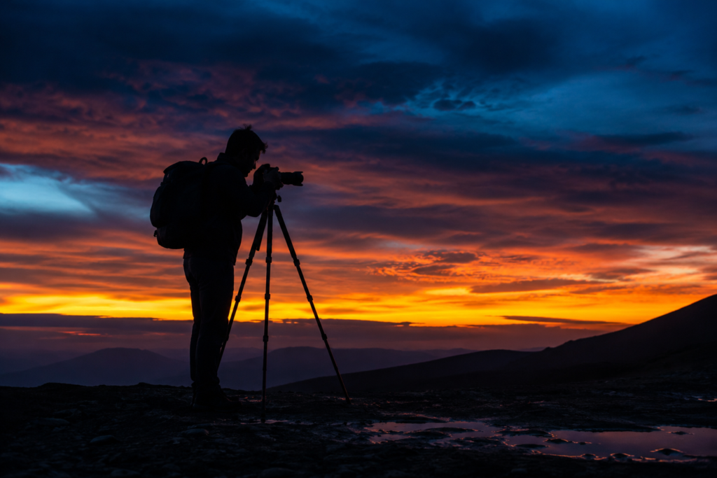 camping photography tips photographer silhouette with tripod at twilight long exposure shot glowing horizon after sunset