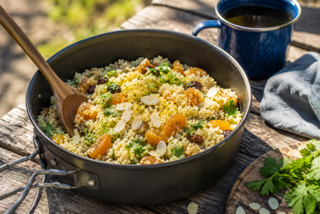 easy camp cooking beginners couscous meal with dried apricots almonds olive oil herbs in pot outdoors