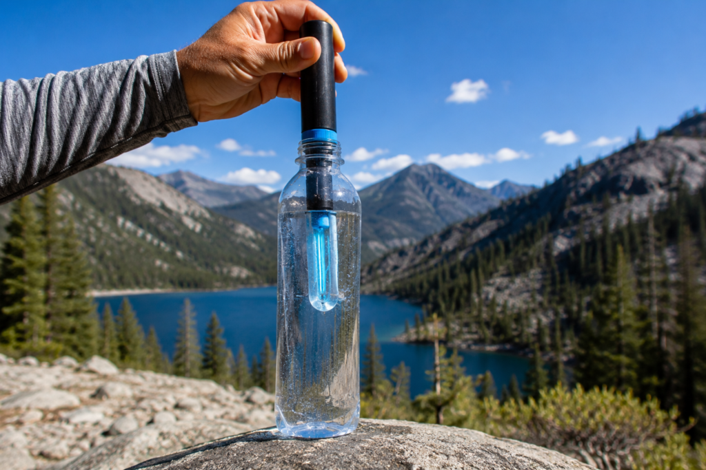 purifying water in the wilderness UV SteriPen purifier inserted into clear water bottle stirring 60 seconds