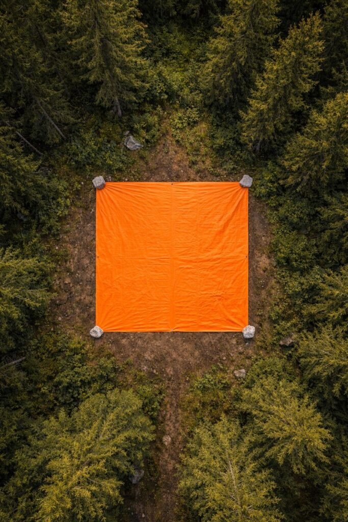 High-visibility orange tarp used as visual emergency signal in wilderness clearing