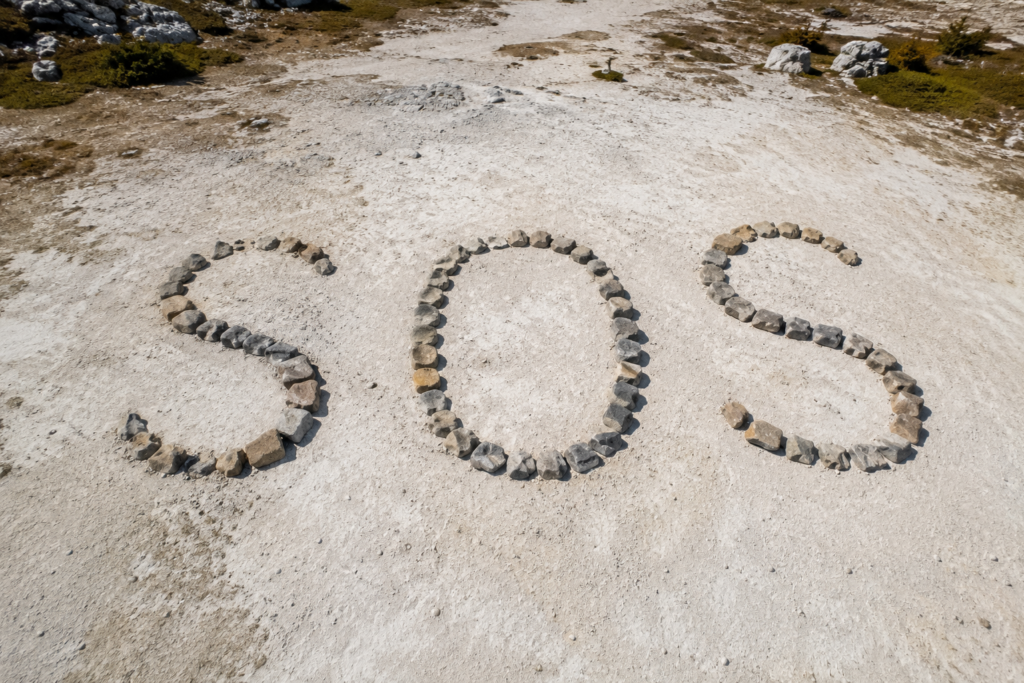 emergency signaling lost campers SOS ground to air marker made from rocks large letters visible from above aerial rescue